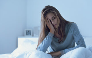 Depressed woman awake in the night, she is touching her forehead and suffering from insomnia
