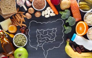 An arrangement of healthy fruits and vegetables surrounding a chalk illustration of intestines